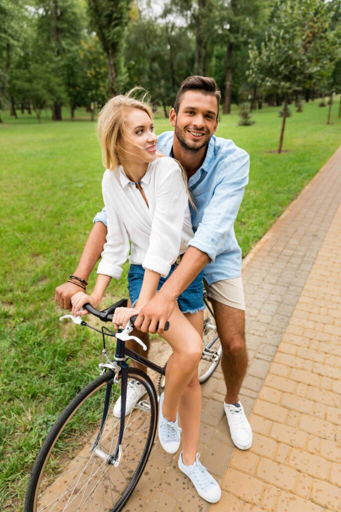 smiling couple riding bicycle together in park 2023 02 17 22 53 06 utc